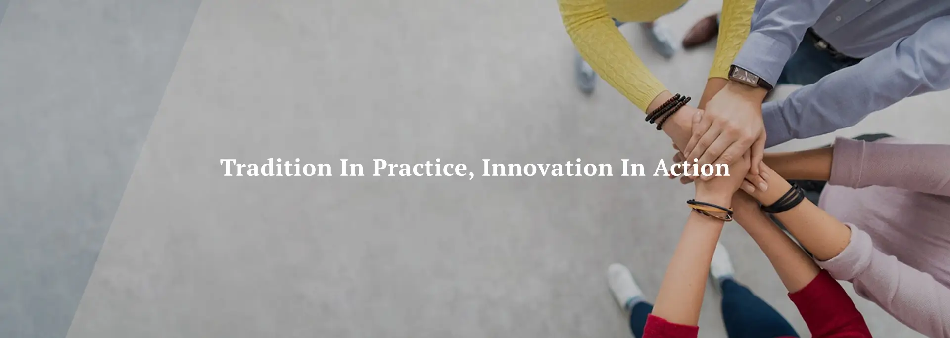 A group of people place their hands on top of each other in a gesture of teamwork and unity.